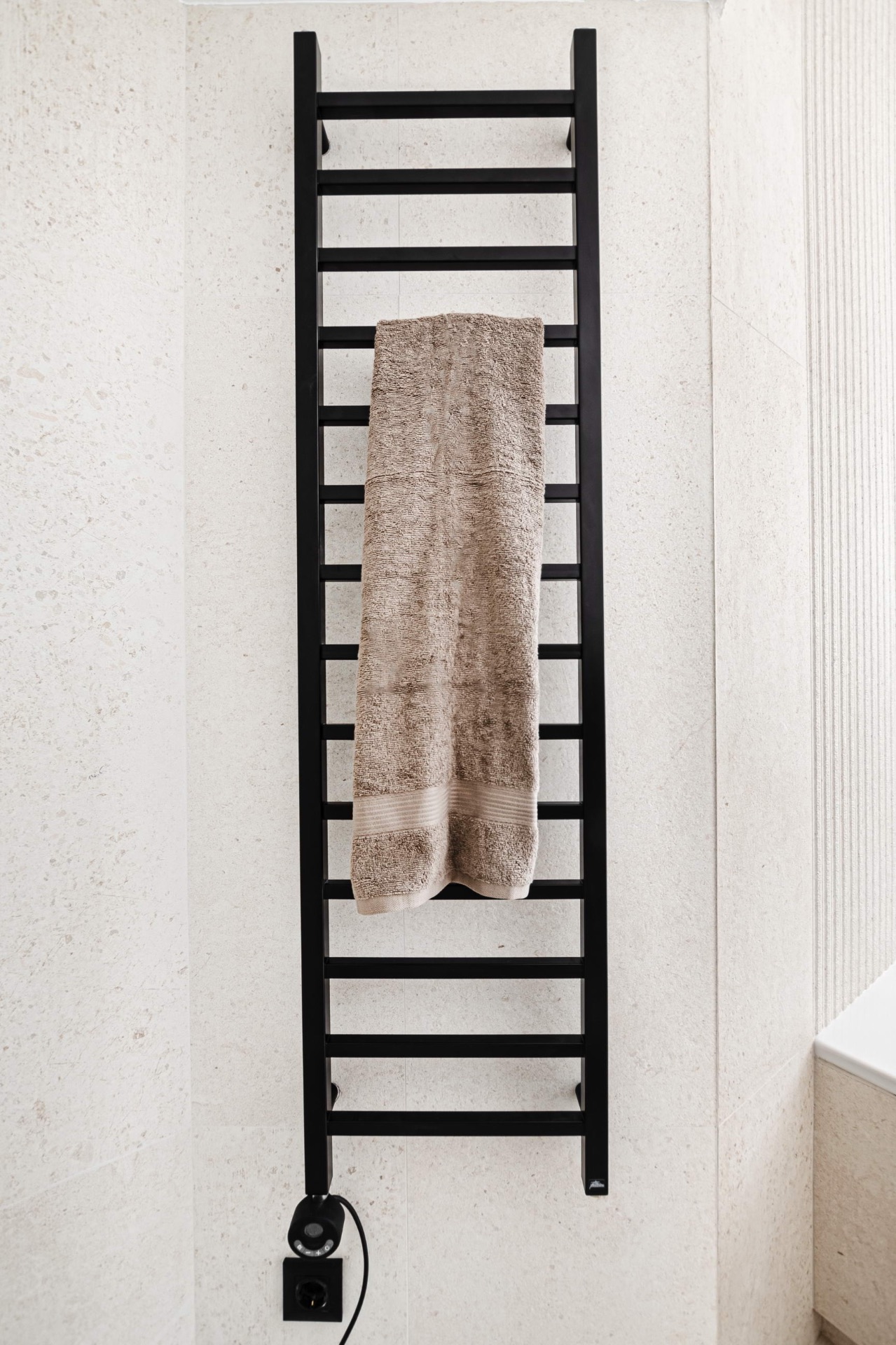 Black towel warmer on stone wall
